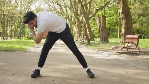 Young Man Stretching in Park on a Sunny Day