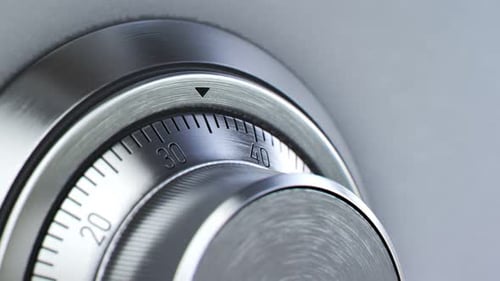 Mechanical dial combination safe full of gold bars mounted on a white wall.