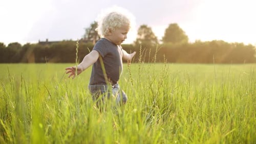 Cute Blond Child Playing in Grassy Field