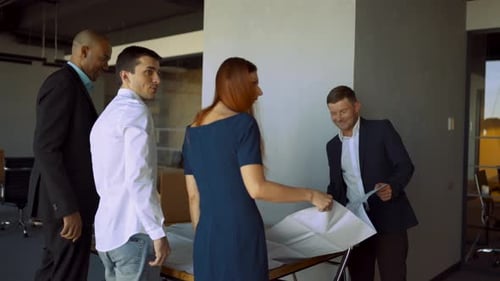 Team Examining Blueprints Together in Modern Office