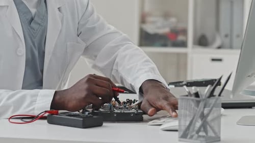 Manos del ingeniero electrónico trabajando con multímetro y computadora