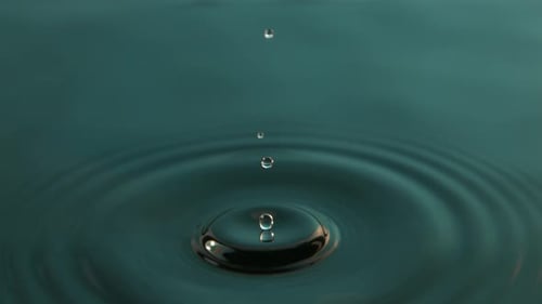 Water Droplets Creating Ripples in Teal Water
