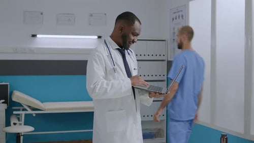 African American Therapist Doctor Standing in Hospital Office Holding Tablet Computer