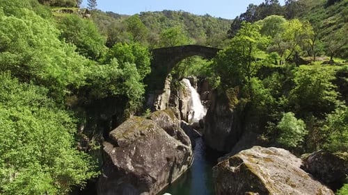 Scenic Waterfall Flowing Underneath an Old Stone Bridge