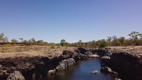 Drone flying above rocky gorge. Camera titls down and pans slightly to look down into gorge. Locatio