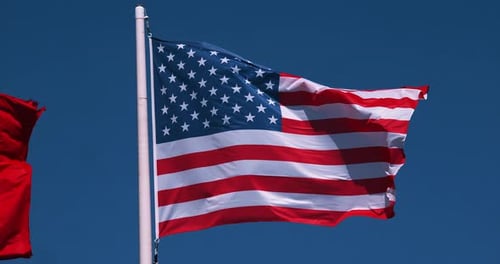 American Flag Waving Against Blue Sky Background
