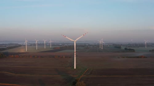Drone Shot on a Wind Farm Tower in a Field at Sunrise with Fog