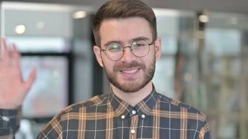 Man Smiling and Waving Hello in an Office