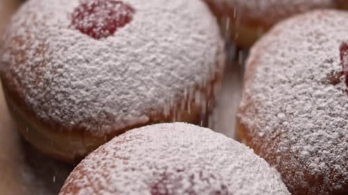 Spreading sugar powder on hanukkah jelly doughnuts, slow motion