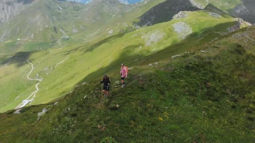 Aerial: couple backpackers hiking on mountain top Summer adventures on the Alps