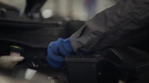 Nahaufnahme männlicher Hände in Schutzhandschuhen, die den Motorluftfilter abnehmen und wieder hineinstecken
