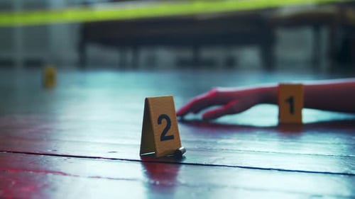 Hand near evidence marker in crime scene