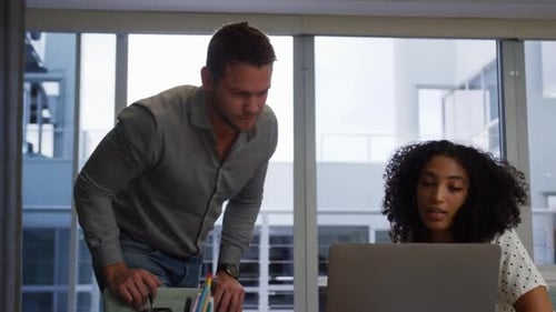 Young office executives discussing over laptop in a modern office