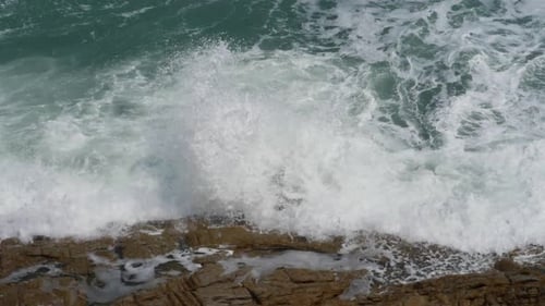 Waves Crashing on Rocky Coastline on Sunny Day