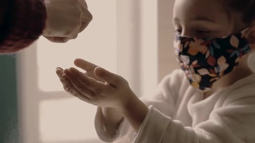 Mãe está higienizando as mãos da filha