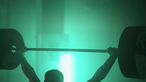 Athletic Man Lifting a Barbell at Gym During Cross Training