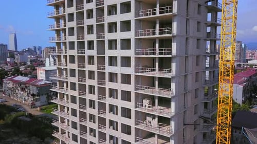 Grúa de construcción en el sitio de construcción con montañas y ciudad como telón de fondo.