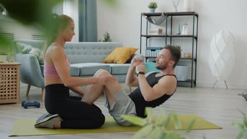 Slow Motion of Joyful Young People Couple Training Together in Apartment Exercising on Yoga Mat