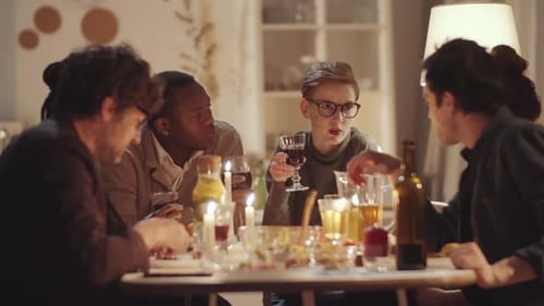 Multi-Ethnic Friends Eating Holiday Dinner, Speaking and Toasting with Wine