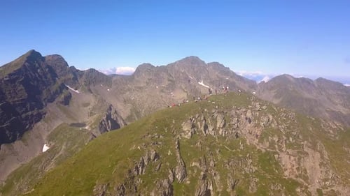 Vue aérienne descendante de randonneurs au sommet de la montagne surplombant un vaste paysage majestueux avec bl