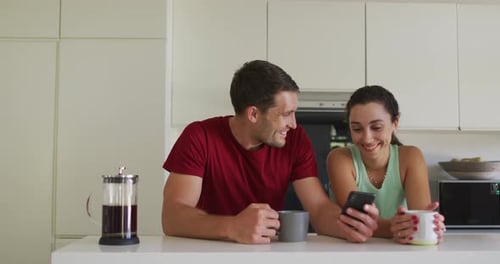 Smiling Couple Looking at Phone in Kitchen