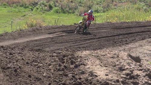 A young man riding a motocross dirt bike.