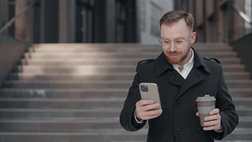 Geschäftsmann schreibt Textnachricht auf dem Smartphone und hält eine Tasse Kaffee in der Hand