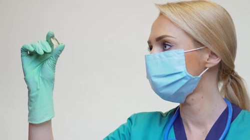 Woman in Mask Examining Pill in Hospital Setting