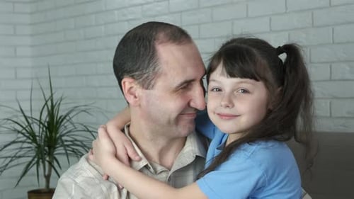 Father and Daughter Smiling and Embracing Indoors