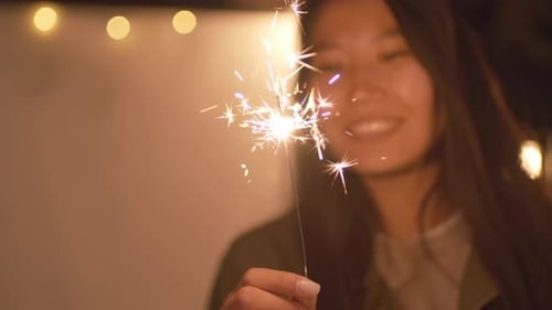 Woman Smiling Holding Sparkler at Night Party
