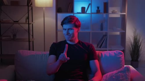 Man Wags Finger with a Smirk on Couch