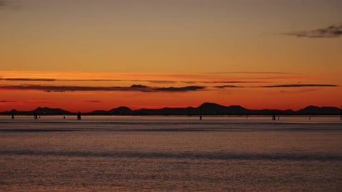 Sea Against Distant Lights on Mountainous Terrain at Sunset