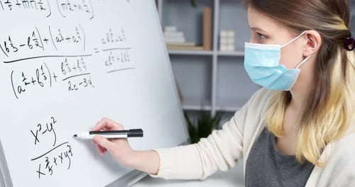 Young Adult Writes Math Equations on Whiteboard