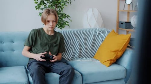 Teenager Plays Video Game on Couch at Home