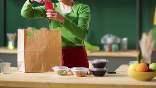 Mujer descargando alimentos y bebidas ecológicos de una bolsa de papel en casa