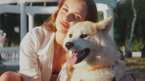 Young woman walking her cute Akita Inu dog in park on sunny day. Lovely pet