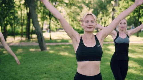 Women Exercising and Stretching in Park