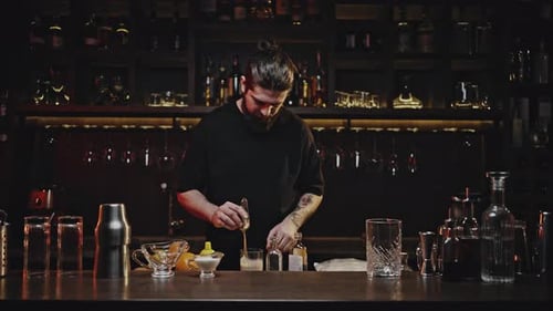 Barman profesional agita el cóctel en vaso con espátula