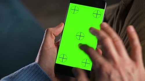 Man Using Smartphone with Green Mockup Screen in Vertical Mode