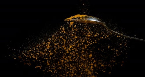 Spoon and Curry Powder falling against Black Background, Slow motion 4K