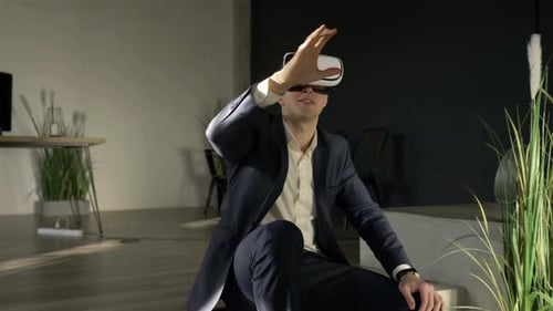 businessman in glasses of virtual reality is sitting on the floor in the office