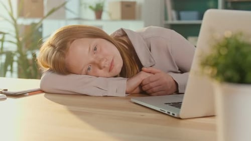 Tired Teenage Schoolgirl While Studying Online at a Laptop