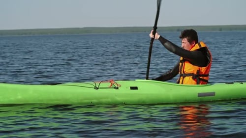 Solo Kayaker Paddling on a Sunny Lake