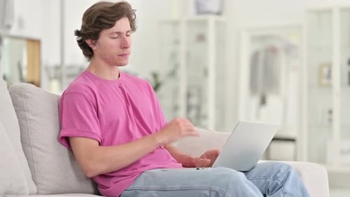 Young Adult Massaging Neck While Using Laptop