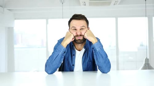 Man with Head in Hands at Table Indoors