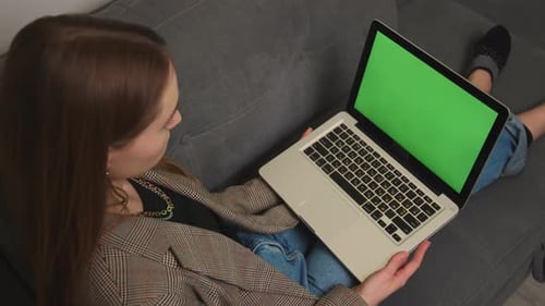 Caucasian Pretty Young Woman Using Laptop with Green Screen Lying on the Couch Sofa at the Home