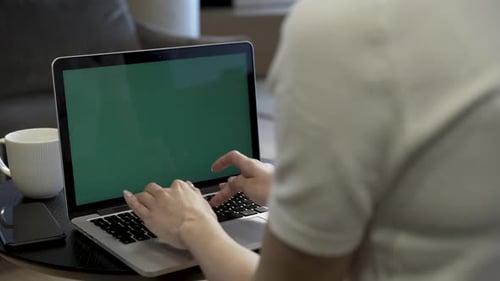 Person Typing Keyboard Of Laptop With Green Screen
