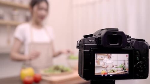 Una mujer asiática bloguera que usa una cámara graba un vídeo de cómo hacer ensaladas y alimentos saludables para su suscriptor.