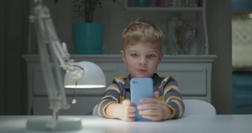 Child Using Phone at Table Indoors