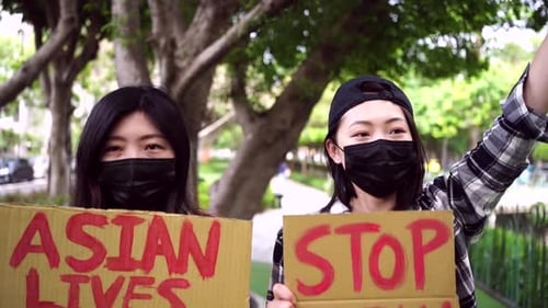 Asian women with posters during protest in city